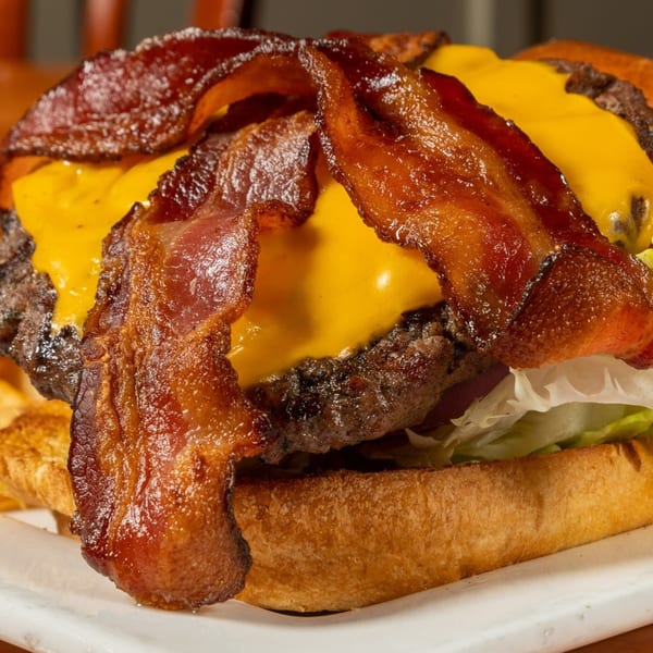 Close-up of a Felix's BBQ with Soul burger, topped with melted cheese and crispy bacon.
