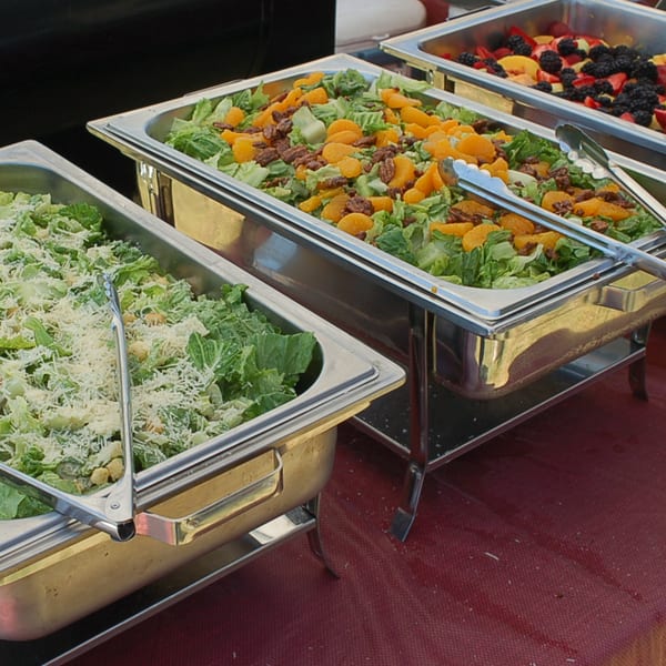 Three buffet trays with Caesar salad, mandarin orange salad, and mixed fruit.