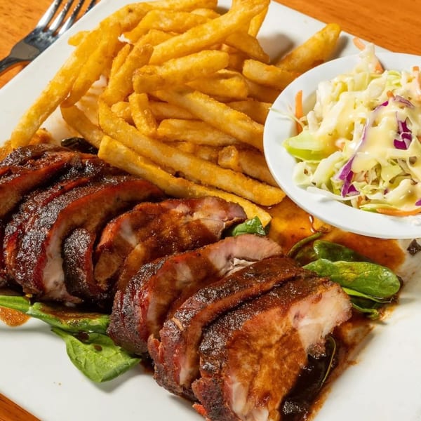 Felix's BBQ with Soul sliced ribs, french fries, and coleslaw on a white plate.