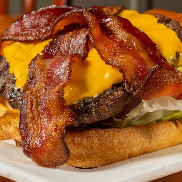 Close-up of a Felix's BBQ with Soul cheeseburger with bacon, melted cheese, and lettuce.