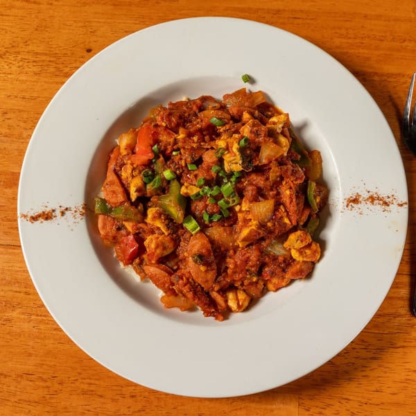 A plate of Felix's BBQ with Soul's jambalaya, featuring chicken, sausage, and vegetables in a rich sauce.