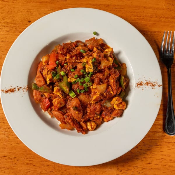 A white plate of Felix's BBQ with Soul jambalaya, featuring sausage, chicken, and vegetables.