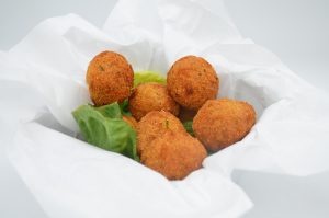 Hushpuppies, a soul food favorite, in a basket on a white background.